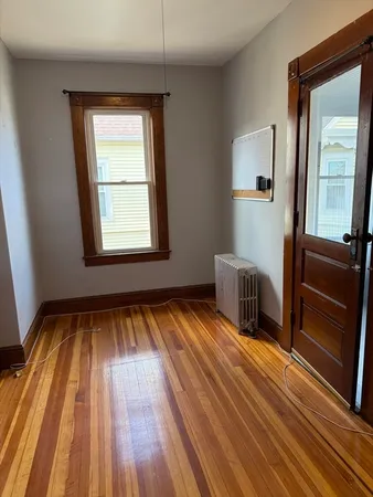 a view of a room with wooden floor and two windows