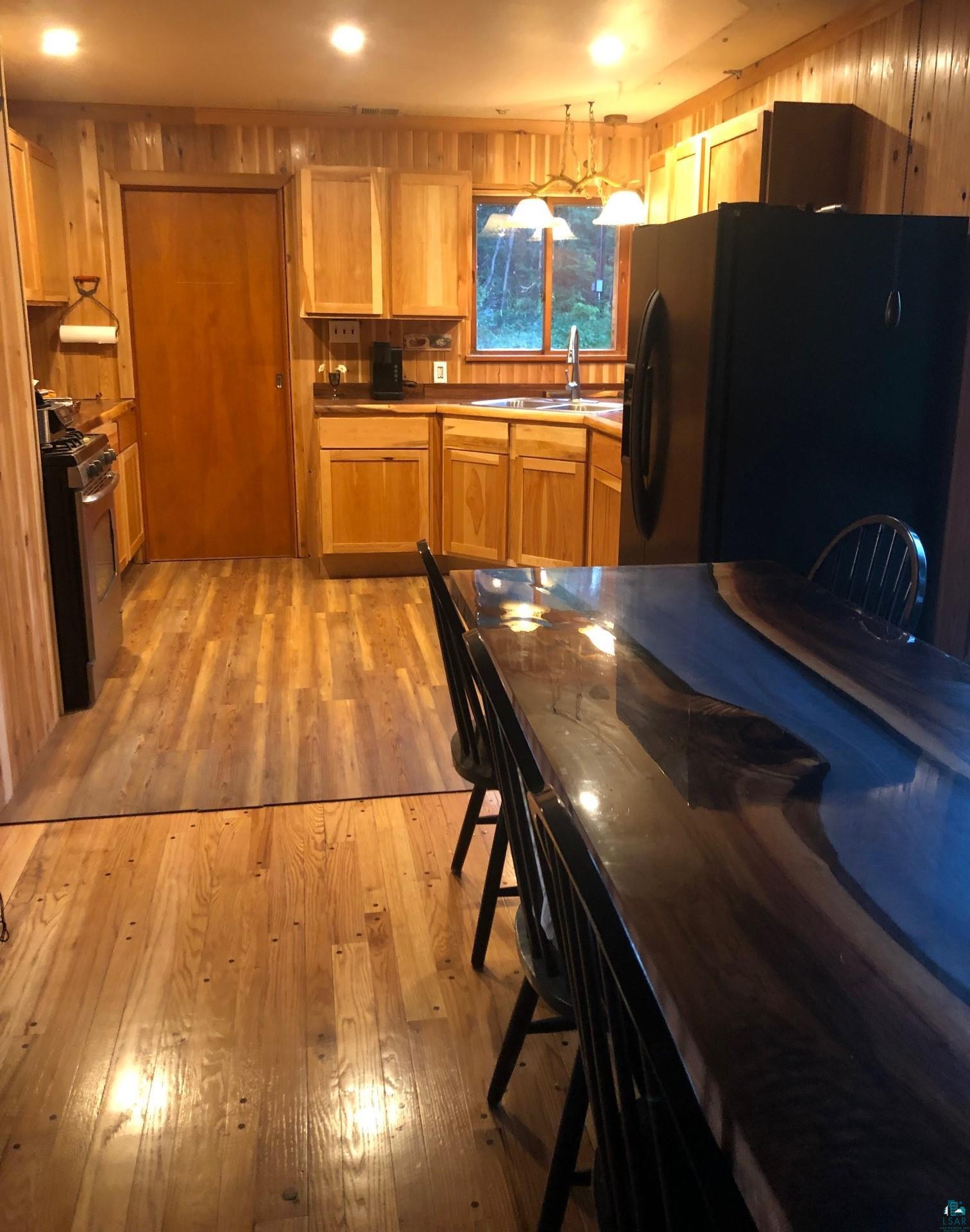 444 Fernberg Road, Unit 11 Ely, MN 55731 - Photo 8 of 19 Kitchen with a sink, light wood finished floors, gas stove, and black fridge