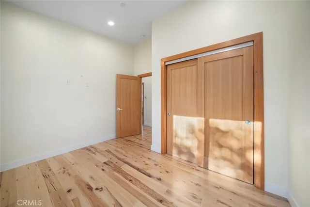 a view of a hallway with wooden floor and a bathroom