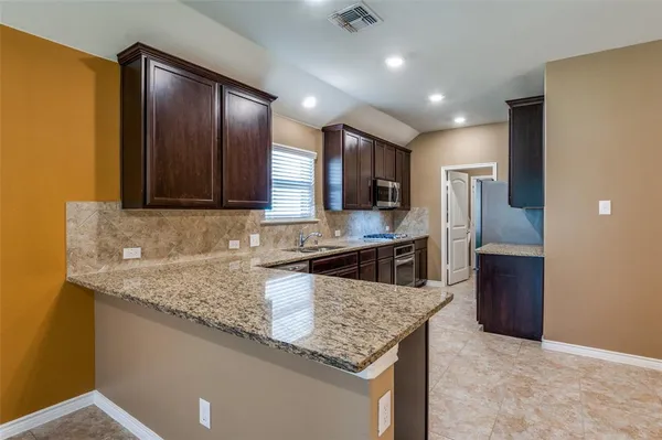 a kitchen with stainless steel appliances granite countertop a sink and a refrigerator
