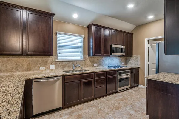 a kitchen with stainless steel appliances granite countertop wooden cabinets a sink and dishwasher