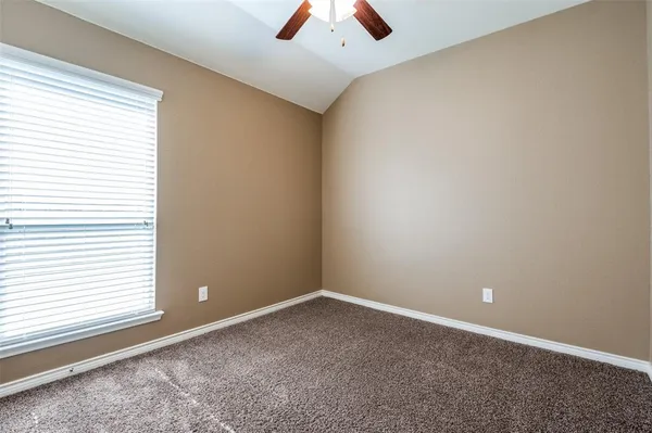 an empty room with a window and a chandelier fan