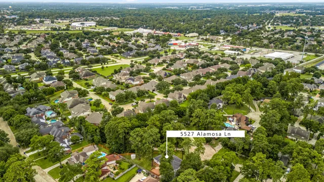an aerial view of residential houses with outdoor space and trees