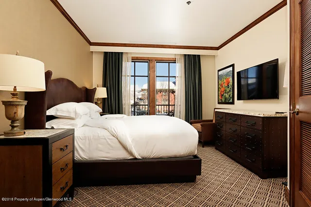 a bedroom with a bed and a flat tv screen on dresser
