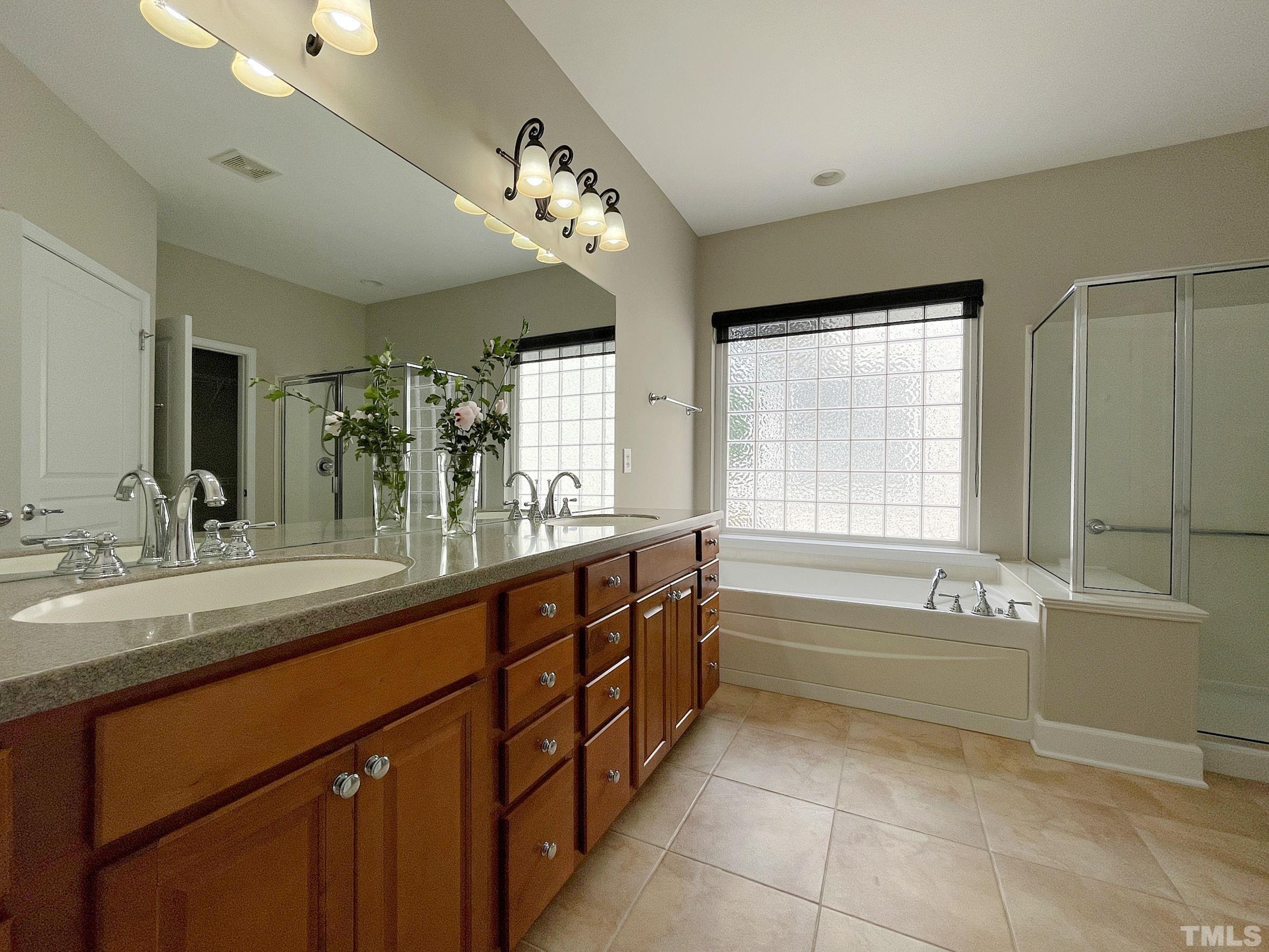 207 Beckingham Loop Cary, NC 27519 - Photo 18 of 40 a spacious bathroom with a sink a large mirror and a bathtub with shower
