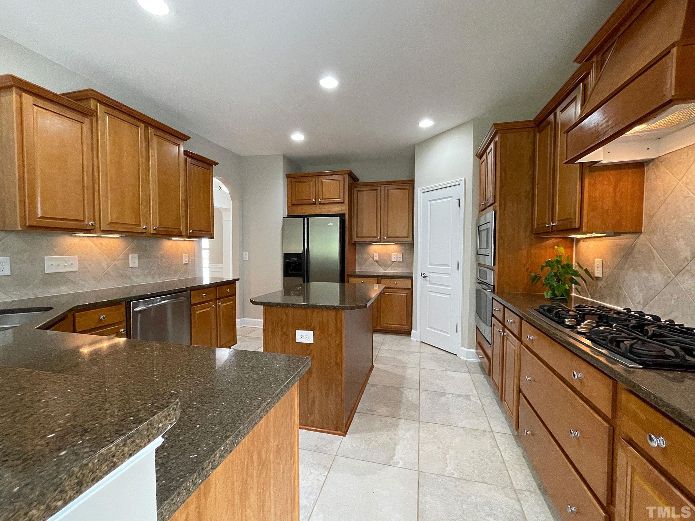 207 Beckingham Loop Cary, NC 27519 - Photo 9 of 40 a kitchen with stainless steel appliances granite countertop a sink stove and refrigerator