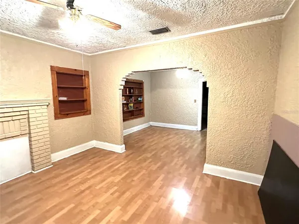 a view of an empty room with wooden floor and a window