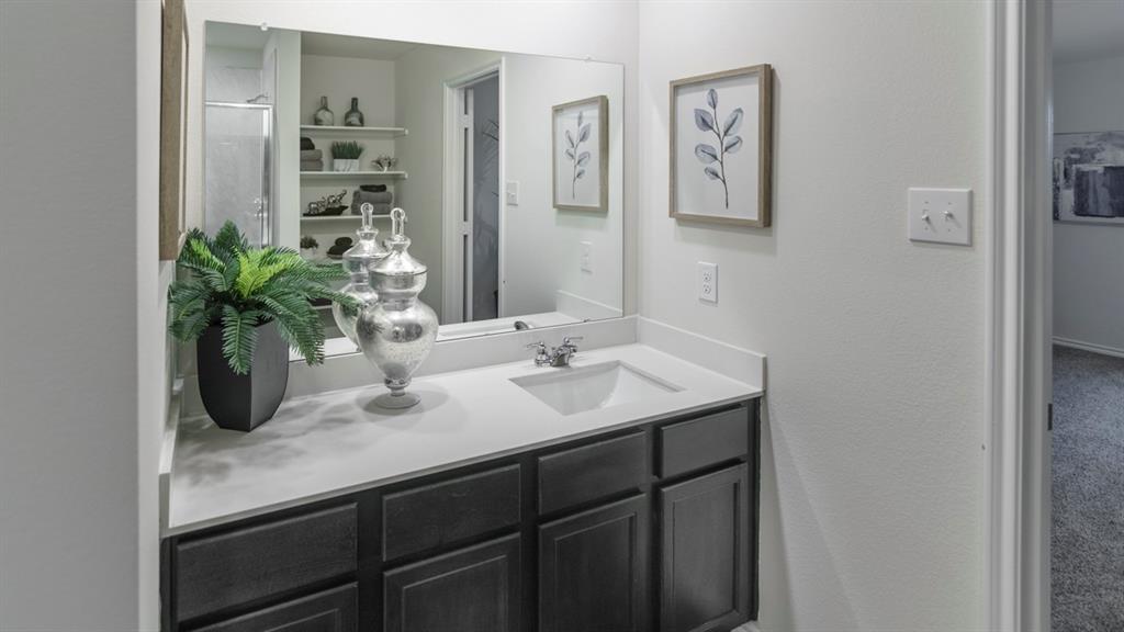 3100 Charleston Drive Ennis, TX 75119 - Photo 13 of 23 Bathroom vanity with an integrated sink, a large wall-mounted mirror, and dark wood-finish cabinetry