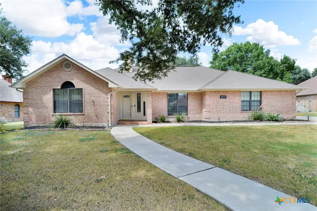 a front view of a house with a yard and trees