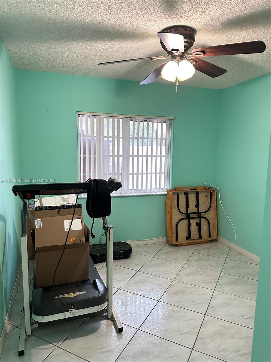 15318 Southwest 41st Terrace Miami, FL 33185 - Photo 19 of 30 a room with gym equipment and a chandelier
