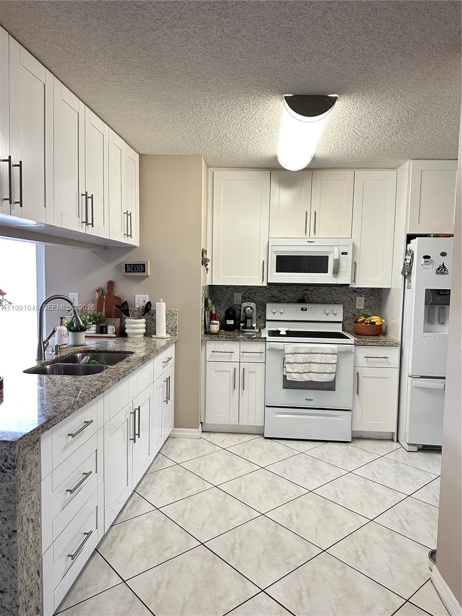 15318 Southwest 41st Terrace Miami, FL 33185 - Photo 7 of 30 a kitchen with granite countertop white cabinets and white appliances