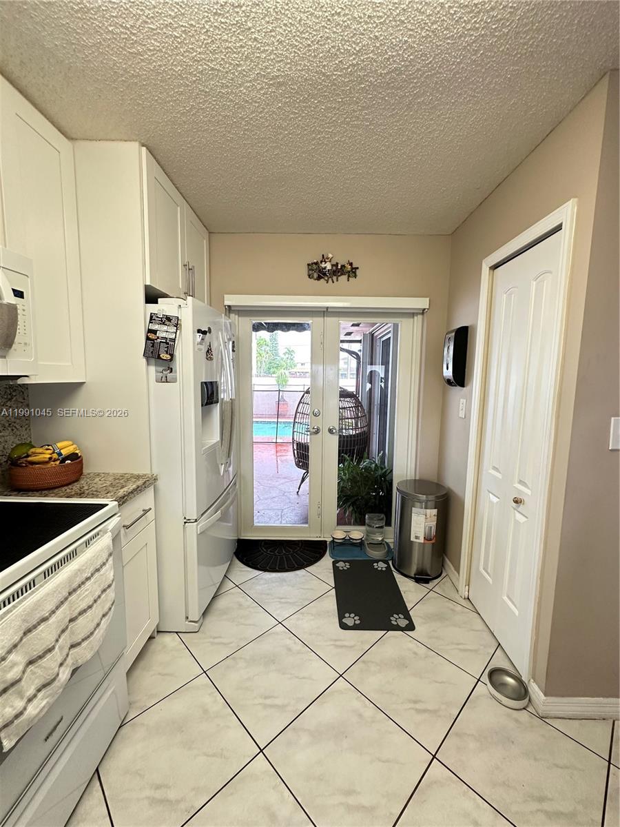15318 Southwest 41st Terrace Miami, FL 33185 - Photo 8 of 30 a kitchen with granite countertop a refrigerator and a stove top oven