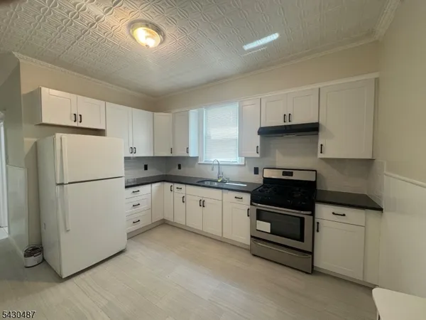 a kitchen with granite countertop white cabinets and white appliances
