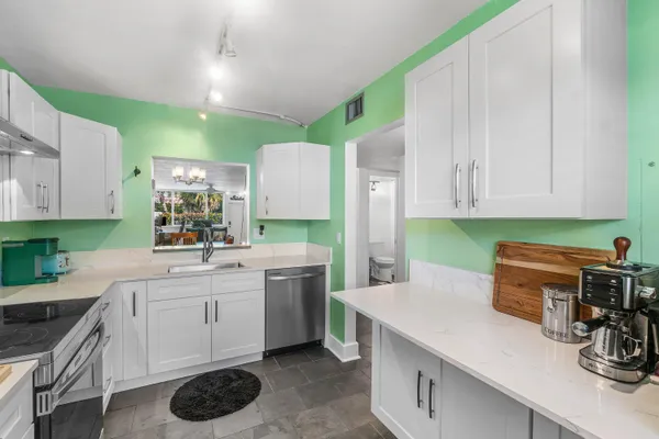 a kitchen with a sink dishwasher stove and white cabinets with wooden floor