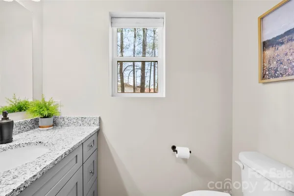 a bathroom with a granite countertop sink a mirror and a toilet