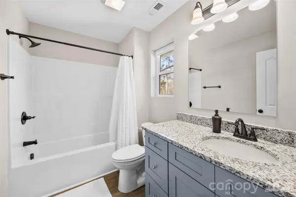 a bathroom with a granite countertop sink toilet and shower