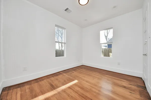 an empty room with wooden floor and windows