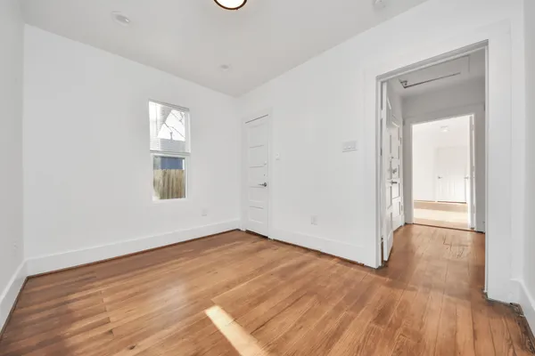 an empty room with wooden floor and windows