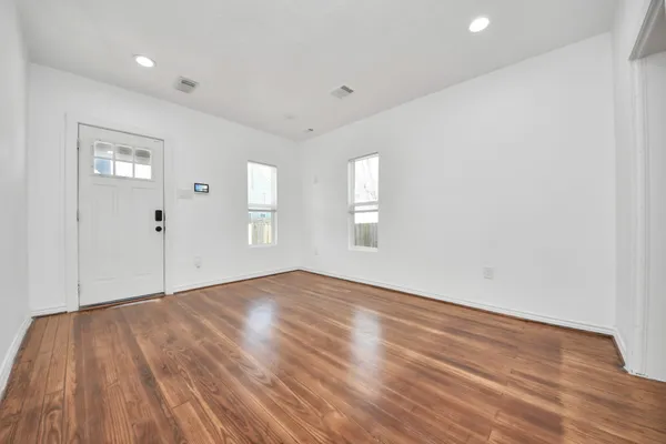 an empty room with wooden floor and windows