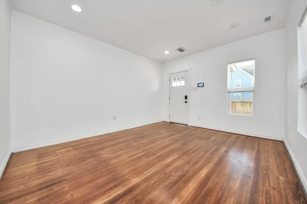 an empty room with wooden floor and windows