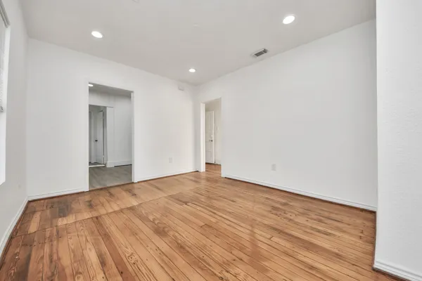 a view of an empty room with wooden floor and a window