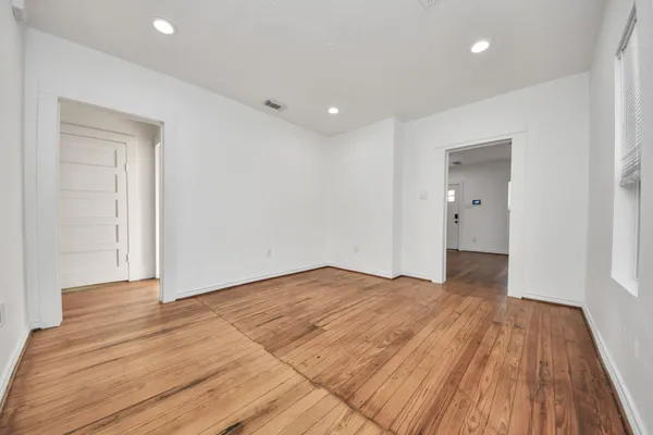 a view of an empty room with wooden floor and closet