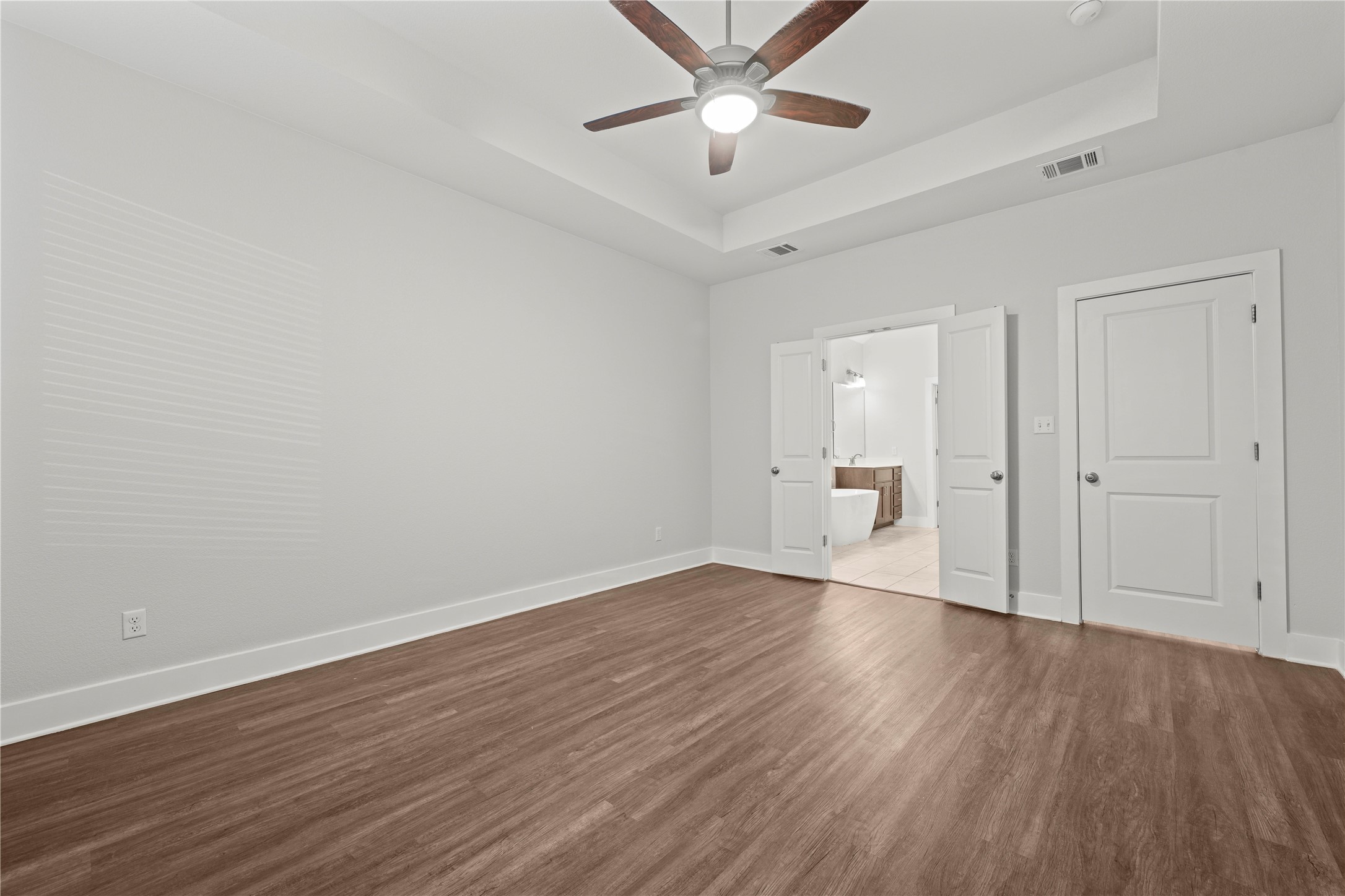 60 Rancho Trail Georgetown, TX 78628 - Photo 15 of 36 Rich wood floors and a tray ceiling define this elegant main bedroom suite.