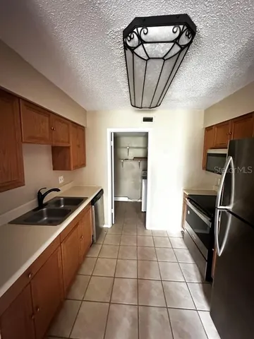 a kitchen with granite countertop a stove a sink and a refrigerator