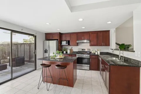 a kitchen with kitchen island granite countertop wooden cabinets a stove a sink and a stainless steel appliances