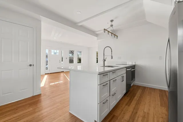 a kitchen with sink a refrigerator and wooden floor