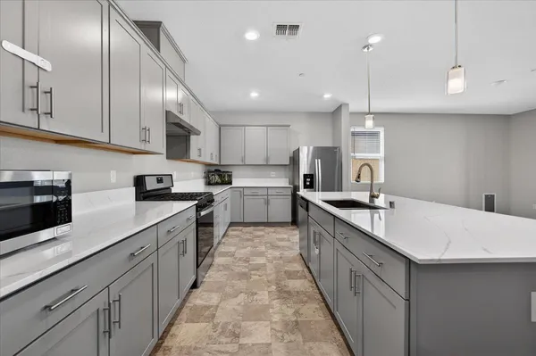 a large kitchen with stainless steel appliances kitchen island granite countertop a sink a stove and cabinets
