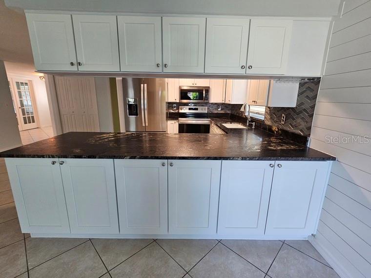 7313 Hatteras Drive Hudson, FL 34667 - Photo 12 of 33 a kitchen with stainless steel appliances granite countertop a refrigerator a sink a stove and white cabinets
