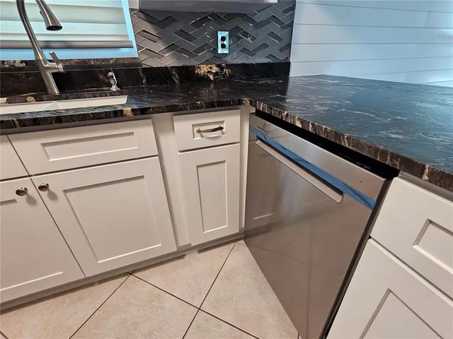 a kitchen with stainless steel appliances granite countertop a refrigerator a sink a stove and white cabinets