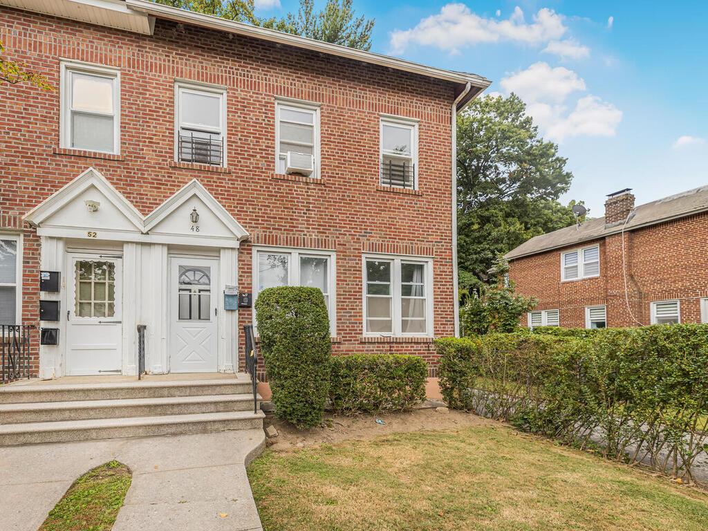 Townhome / multi-family property with a front lawn and brick siding