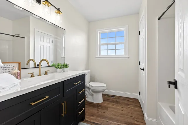 a bathroom with a granite countertop sink toilet a mirror a vanity and shower
