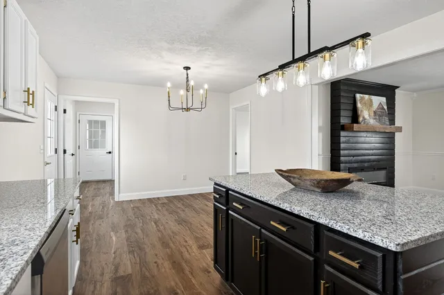 a kitchen with stainless steel appliances granite countertop a refrigerator a sink dishwasher a stove and white cabinets with wooden floor