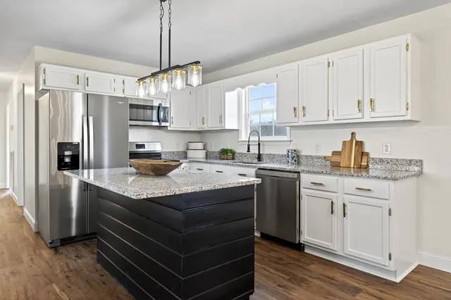 a kitchen with granite countertop a sink stainless steel appliances and white cabinets