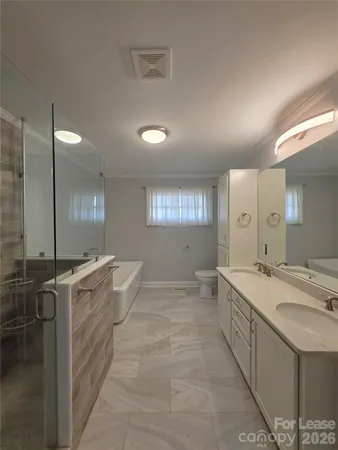 a large bathroom with a granite countertop sink a toilet a mirror and shower