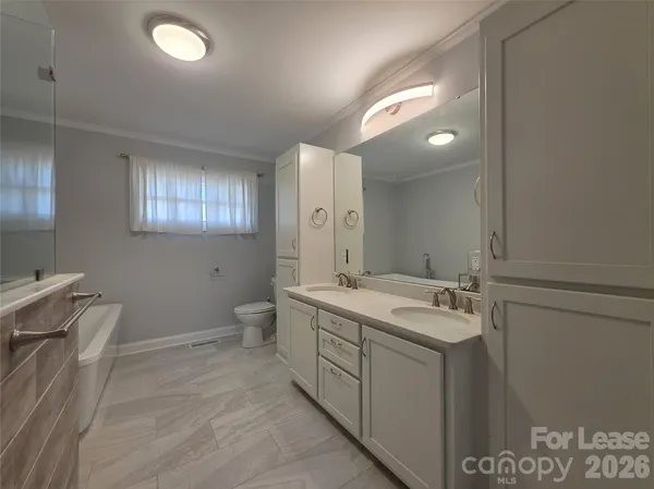 a view of a bathroom with double vanity sink a mirror and a toilet