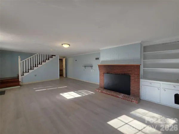a view of an empty room with a fireplace and a window