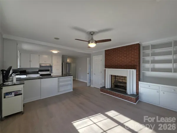 a large white kitchen with a stove a sink a refrigerator and a fireplace