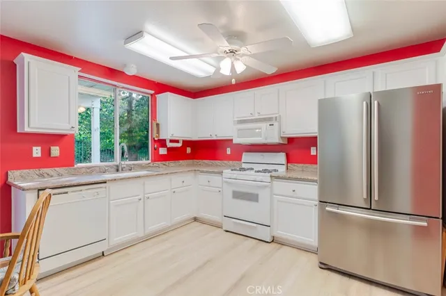 a kitchen with granite countertop a refrigerator sink stove top oven and cabinets