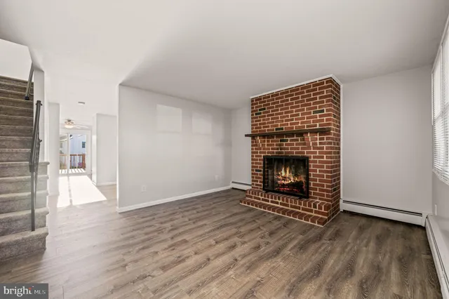 an empty room with wooden floor a fireplace and windows