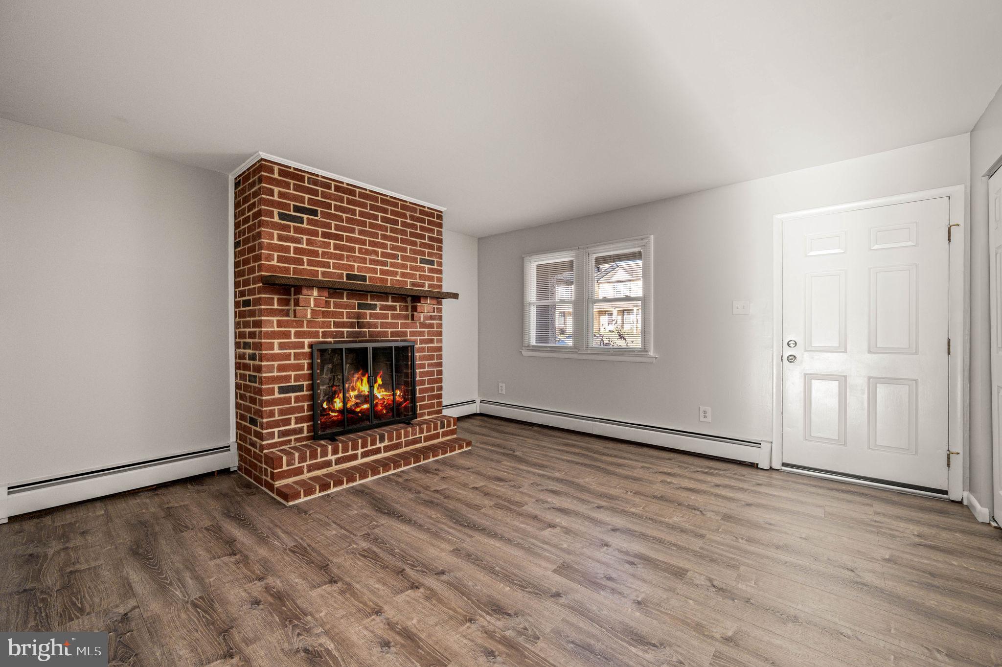 2404 Walnut Ridge Drive Pottstown, PA 19464 - Photo 4 of 24 an empty room with wooden floor a fireplace and windows