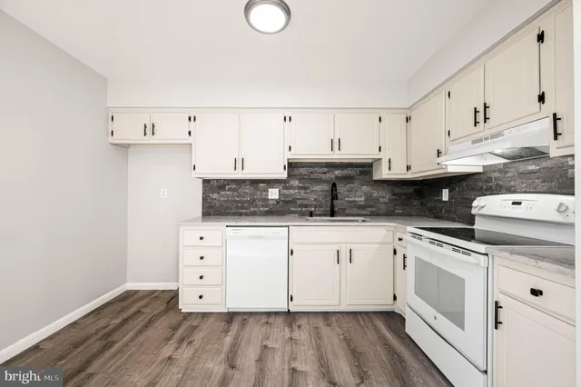 a kitchen with cabinets stainless steel appliances a sink and wooden floor