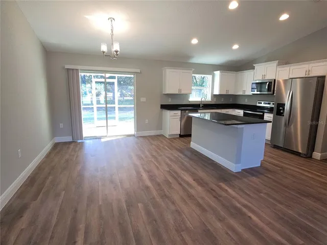 a kitchen with stainless steel appliances granite countertop a stove top oven a refrigerator with wooden floors and cabinets