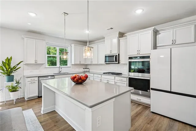 a kitchen with a refrigerator a stove a sink and white cabinets with wooden floor