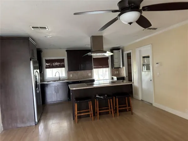 a kitchen with stainless steel appliances a dining table chairs and wooden floor