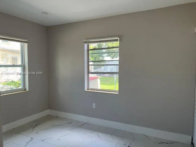 an empty room with a window and wooden floor
