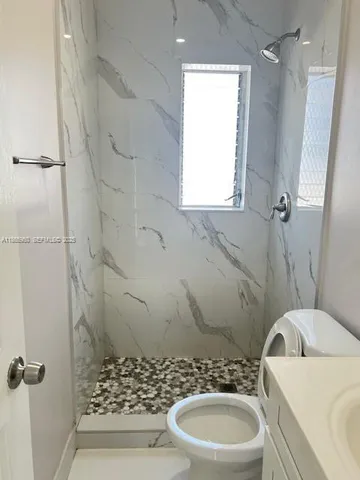 a bathroom with a sink a toilet a window and shower
